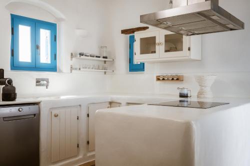a kitchen with white cabinets and blue accents at Cemilion in Koufonisia