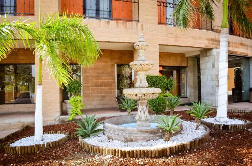 a fountain in front of a building with palm trees at Hotel Colonial Hermosillo in Hermosillo