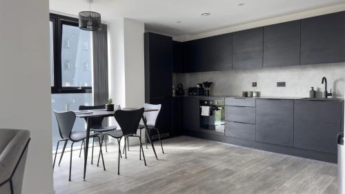 a kitchen with black cabinets and a table and chairs at Luxury Apartment by Noire Property in Manchester