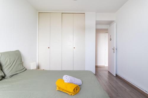 Un dormitorio con una cama con una toalla amarilla. en Appartement proche du Vieux Lille avec une vue exceptionnelle sur la Ville !, en La Madeleine