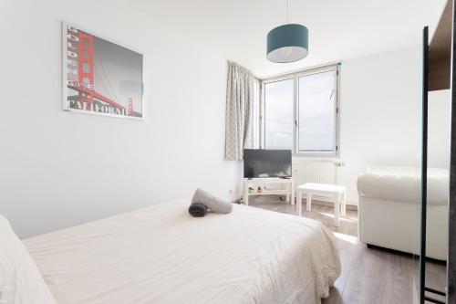 1 dormitorio blanco con 1 cama y 1 silla en Appartement proche du Vieux Lille avec une vue exceptionnelle sur la Ville !, en La Madeleine