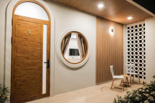 a hallway with a wooden door and a round mirror at Wantanee Ville วันทนีย์วิลล์ in Ban Wang Sai