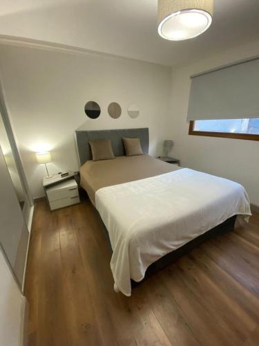Schlafzimmer mit einem großen weißen Bett und Holzböden in der Unterkunft Departamento en el Corazon de Bariloche in San Carlos de Bariloche