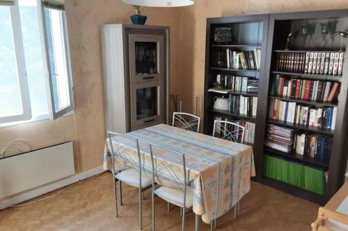 a dining room with a table and chairs and a book shelf at Grand T1 meublé in Saint-Flour