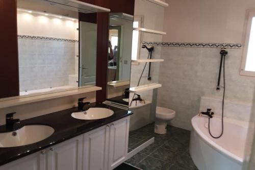 une salle de bain avec deux lavabos et une baignoire et des toilettes dans l'établissement Grand T1 meublé, à Saint-Flour