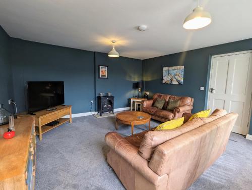 a living room with a couch and a tv at Cockle Cottage - Crabpot Cottages in Cromer
