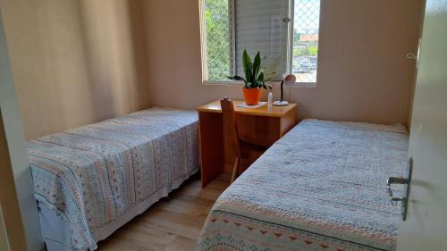 a bedroom with two beds and a desk and a window at Quarto Individual ou Duplo ao lado da Ponte Transamerica in Sao Paulo