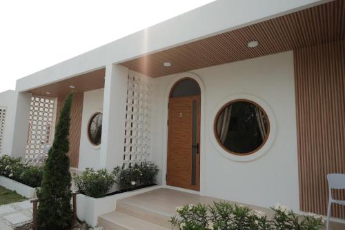 a house with a wooden door and two round windows at Wantanee Ville วันทนีย์วิลล์ in Ban Wang Sai