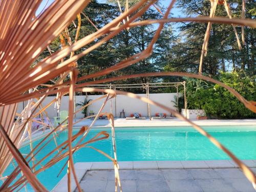 a swimming pool with trees in the background at Ile des Plaisirs - Domaine de Charme et table d'hôtes Caraïbéenne in Graulhet