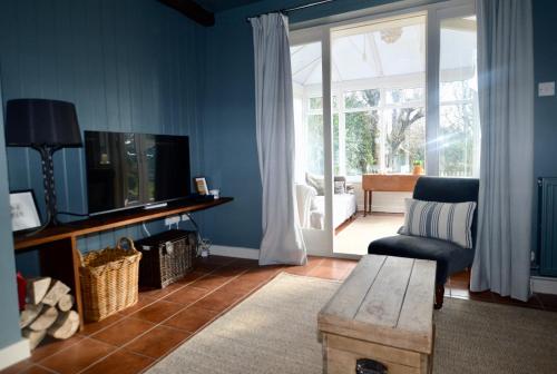 salon z kanapą, telewizorem i krzesłem w obiekcie Gryngolet Cottage - with Artist Studio - Crabpot Cottages Sheringham w mieście Aylmerton