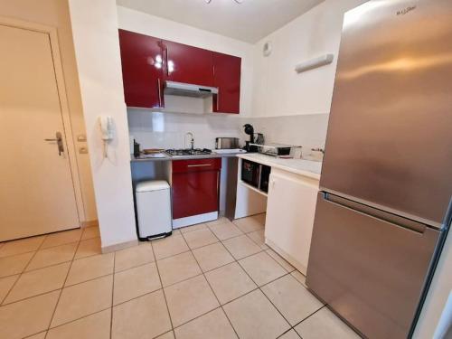 La cuisine est équipée de placards rouges et d'un réfrigérateur en acier inoxydable. dans l'établissement Appartement T2 en centre ville, à La Teste-de-Buch