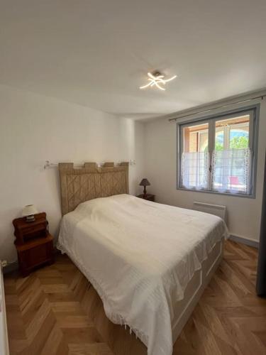 1 dormitorio con cama blanca y ventana en Appartement les Mésanges en Le Poët-Laval