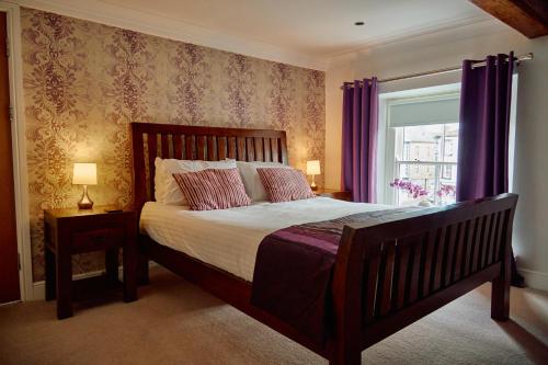 1 dormitorio con 1 cama y una ventana con cortinas moradas en The Pennine Inn en Kirkby Stephen