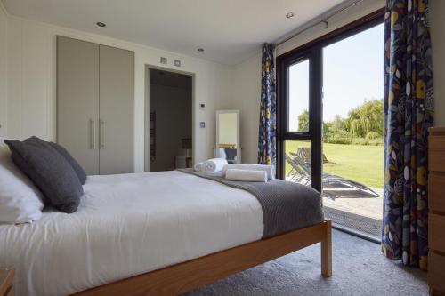 ein Schlafzimmer mit einem großen Bett und einem großen Fenster in der Unterkunft Nunney Lodge in Beckington