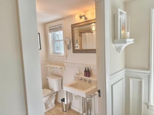 Baño blanco con aseo y lavamanos en Hideaway Inn Maine, en Camden