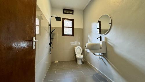 a bathroom with a toilet and a mirror at Green Square Grove - Entire House in Kampala