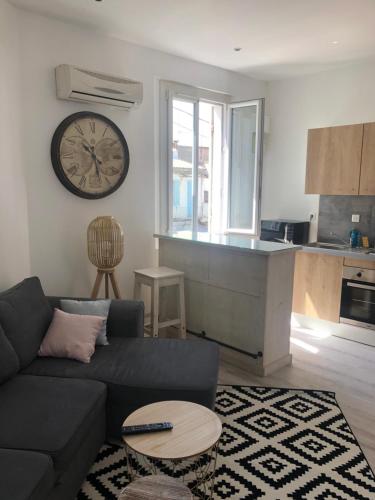 un salon avec un canapé et une horloge au mur dans l'établissement Magnifique T2 bien desservi, à Marseille