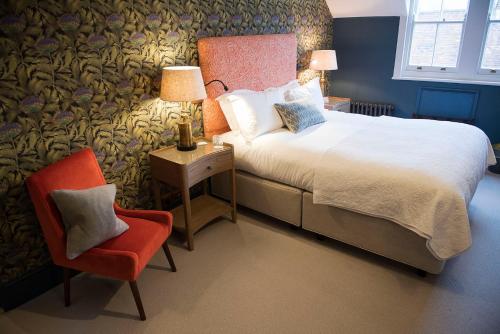 a bedroom with a bed and a red chair at Purchases Restaurant & Accommodation in Chichester