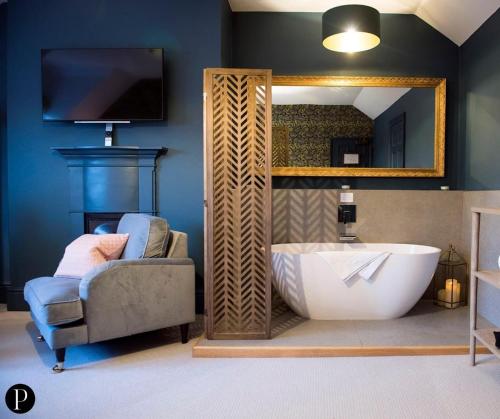 een badkamer met een bad, een stoel en een spiegel bij Purchases Restaurant & Accommodation in Chichester
