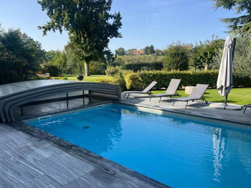 une piscine avec des chaises et un parasol dans l'établissement Gîte L'Escale des Aulnes, à Verneuil