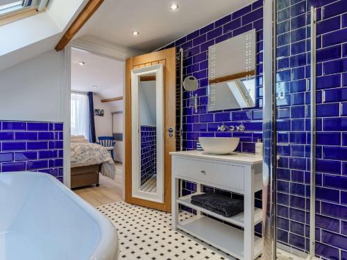 a blue tiled bathroom with a sink and a mirror at 2 bed in Week St Mary 82455 in Week Saint Mary