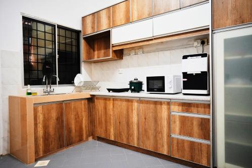 萬撓的住宿－Peach Homestay Tasik Puteri，厨房配有木制橱柜、水槽和微波炉