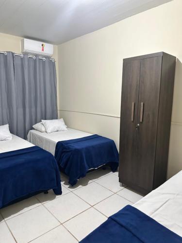 a room with two beds and a wooden cabinet at Hotel Nossa Senhora de Lourdes in Trindade