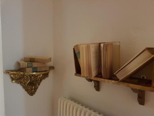 a shelf with books on a wall next to a radiator at B&B La finestra sul bosco in Serralunga di Crea