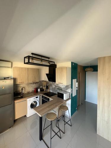 une cuisine avec une table et deux tabourets de bar dans l'établissement Studio élégant avec accès à la piscine, à Nice