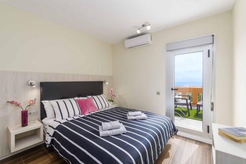 1 dormitorio con 1 cama de rayas azul y blanco y balcón en Villa Krystele, en Caleta de Fuste