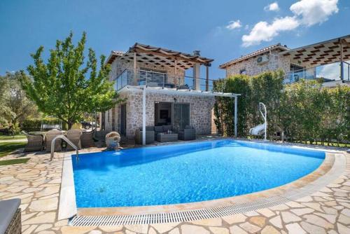 a swimming pool in front of a house at Villas Goudis in Tsoukaladhes