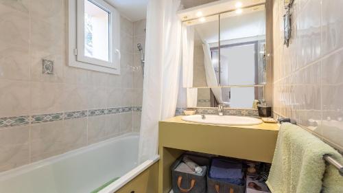 une salle de bain avec un lavabo, une baignoire et un miroir dans l'établissement GREEN VILLAGE -7- Appt Lumineux 4 pers, au Cap d'Agde