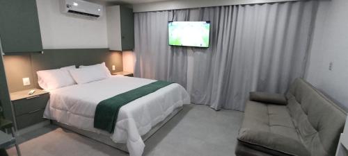 ein Schlafzimmer mit einem Bett und einem Flachbildfernseher in der Unterkunft Flat 304 Porto Prime com Rooftop e Piscina in Porto De Galinhas