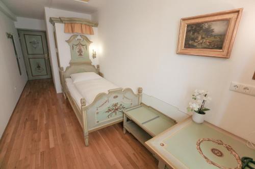 a small bedroom with a bed and a table at Hotel Wilder Mann in Passau