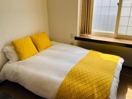 a bedroom with a bed with yellow sheets and a window at Warm House3 in Sapporo