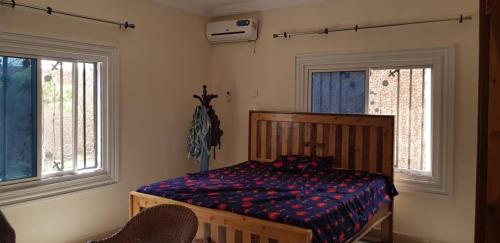 a bedroom with a bed and two windows at Terrouwaar apartment in Sanyang