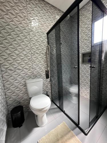 a bathroom with a toilet and a glass shower at A Cozy Little House in a Beautiful Property in Brasilia