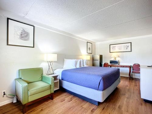 une chambre d'hôtel avec un lit et une chaise dans l'établissement Stayable Jacksonville North, à Jacksonville