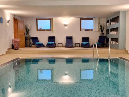 una piscina con sillas azules en una habitación en Karsten Gauselmanns Heißenhof Hotel garni, en Inzell