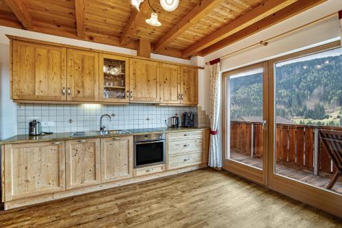 a kitchen with wooden cabinets and a large window at Stoffnerhof Apt Edelweiß in Tesido