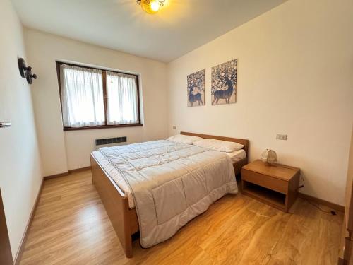 een slaapkamer met een groot bed en een houten vloer bij Appartamenti Doss in Giustino