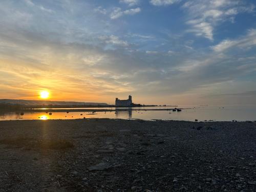 a sunset on a beach with a building in the water at Golf Spa Relax in Collingwood