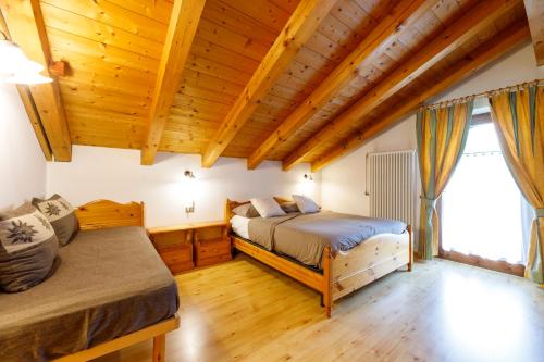 two beds in a room with wooden ceilings at B&B Seppi in Cavalese