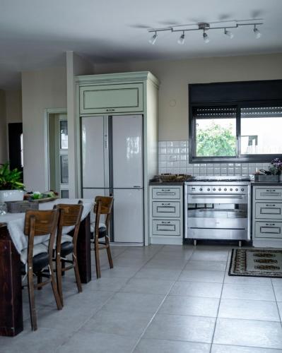 a kitchen with a table and a refrigerator at Ettys Villa in Giv'at Yo'av