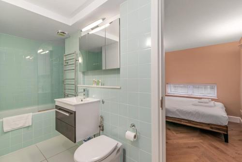 a bathroom with a toilet and a sink and a bed at GuestReady - Beige barley near The British Museum in London