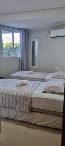 two beds in a white bedroom with a window at EXCELENTE FLAT 2 QUARTOS no BESSA in João Pessoa