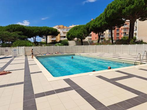 - une piscine avec des personnes assises autour dans l'établissement Studio 4 personnes avec piscine au CAP D AGDE au pied du port et 5 mn à pied de la plage du Môle, au Cap d'Agde