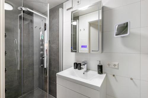 a white bathroom with a sink and a shower at Apartment Am Tobelbach in Oberlenningen