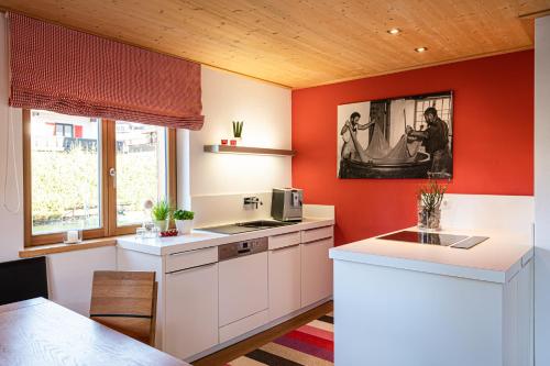 a kitchen with red walls and white cabinets at Krone Chalet in Oberstdorf