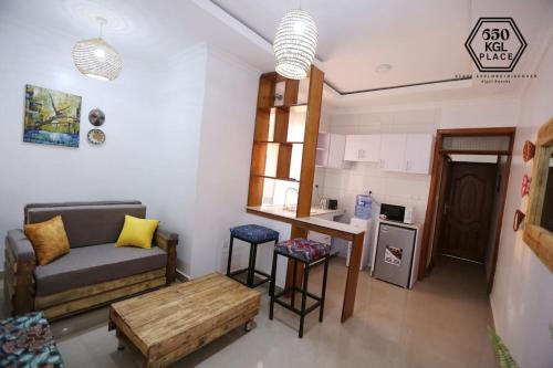 a living room with a couch and a table and a kitchen at Style and Comfort Full Kigali Rwanda Apartment in Kigali